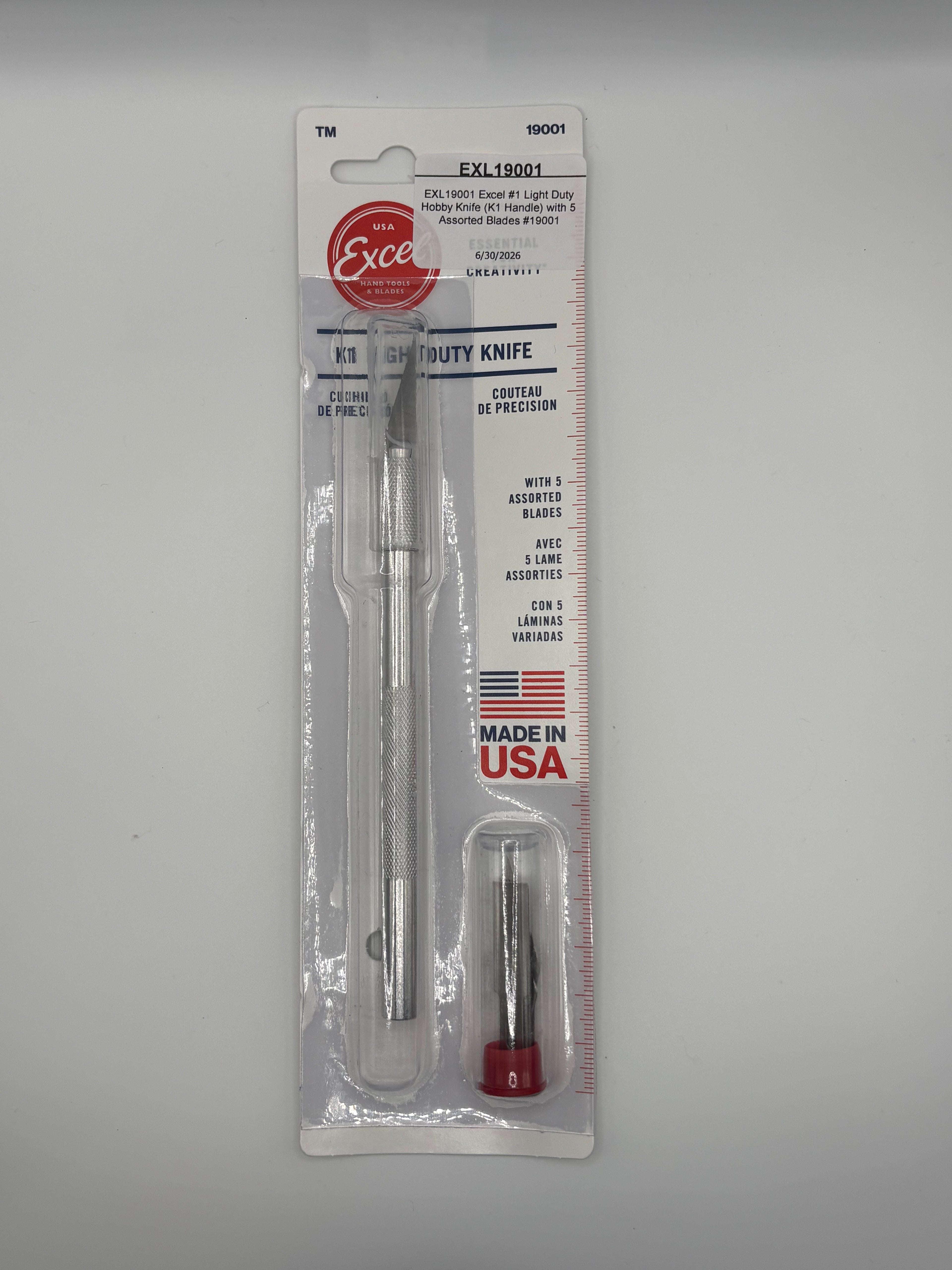 Excel brand straight utility knife in its original retail blister packaging, featuring a silver stainless steel knife and a small red-handled accessory, on a light gray background.